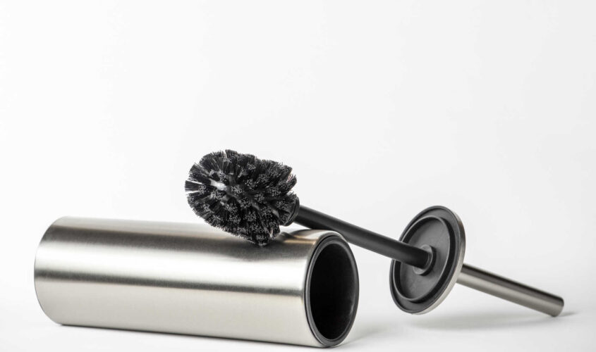 Black toilet brush isolated on white. Close-up of a toilet cleaning brush with metal elements to insert into a project or design. Metal brush for the toilet on a white background.