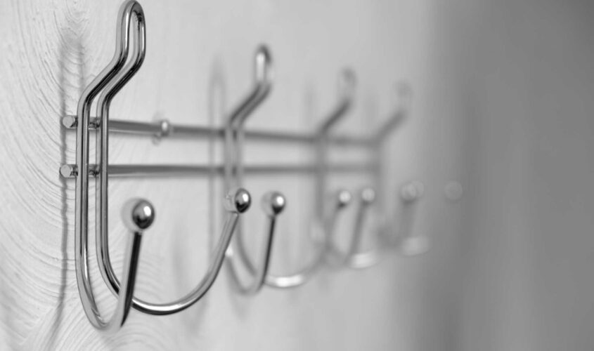 Extremely close-up metal coat hooks on white wall, selective focus