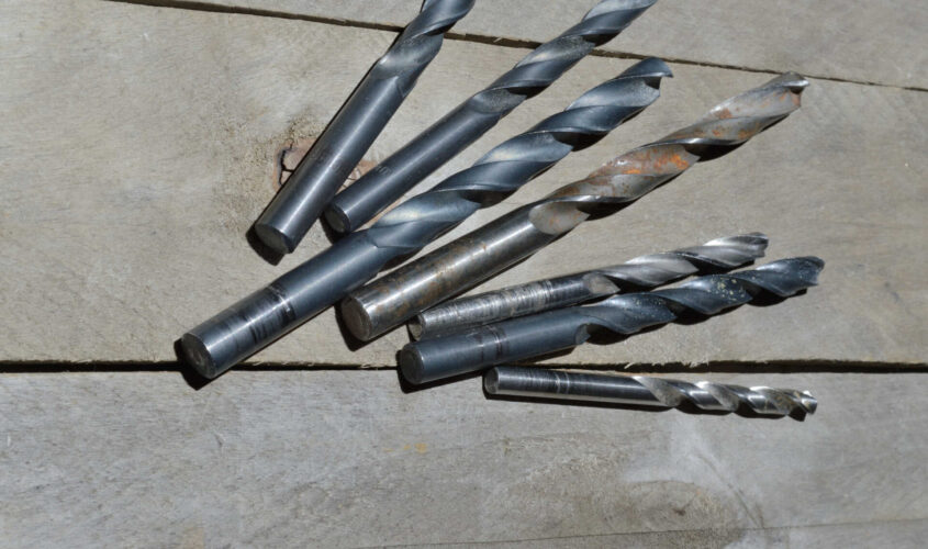 many old drills lie on a plank wooden background. close-up.