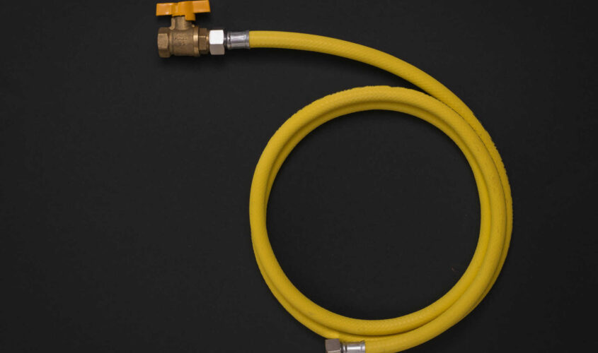 Yellow gas hose with a tap on a black background.
